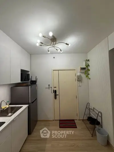 Modern kitchen with sleek appliances and stylish lighting in a compact apartment.