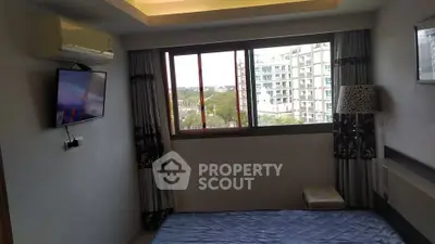 Modern bedroom with large window and city view, featuring a wall-mounted TV and air conditioning.