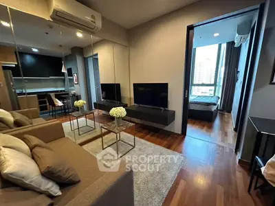 Modern living room with sleek design and open layout leading to a cozy bedroom.