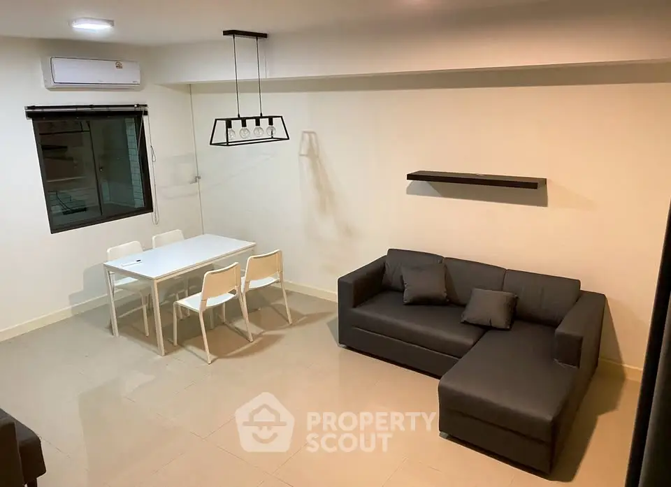 Modern living room with sleek furniture and minimalist design, featuring a cozy sofa and dining area.