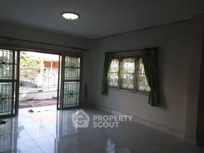 Spacious living room with large windows and tiled floor, offering ample natural light.