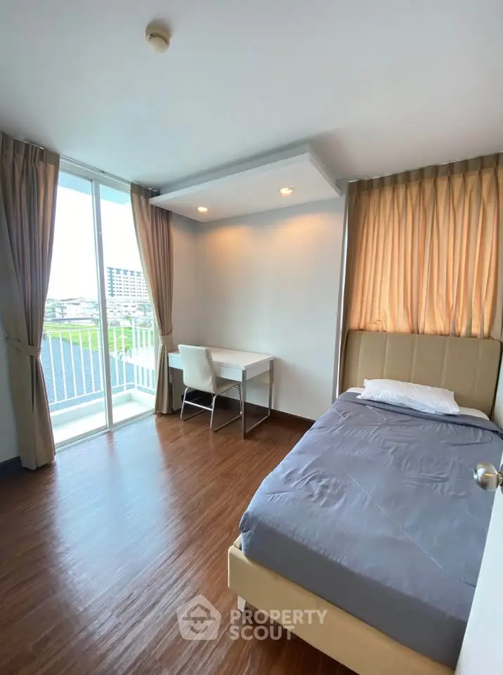 Bright bedroom with single bed, desk, and large window offering a scenic view.