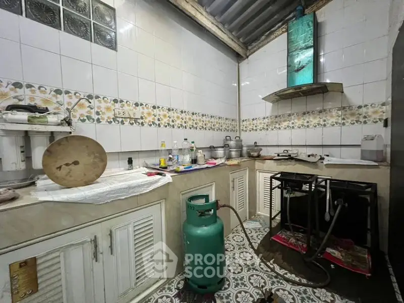 Rustic kitchen with gas stove and traditional decor, featuring tiled backsplash and patterned floor.