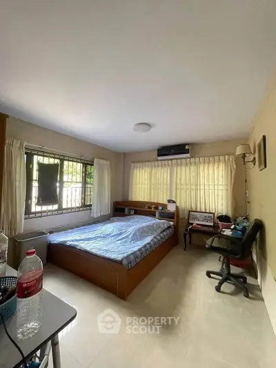 Cozy bedroom with large window and natural light, featuring a comfortable bed and modern furnishings.
