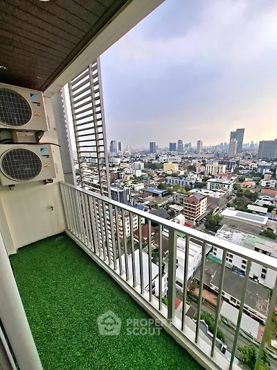 Stunning city view from a high-rise balcony with artificial grass flooring.