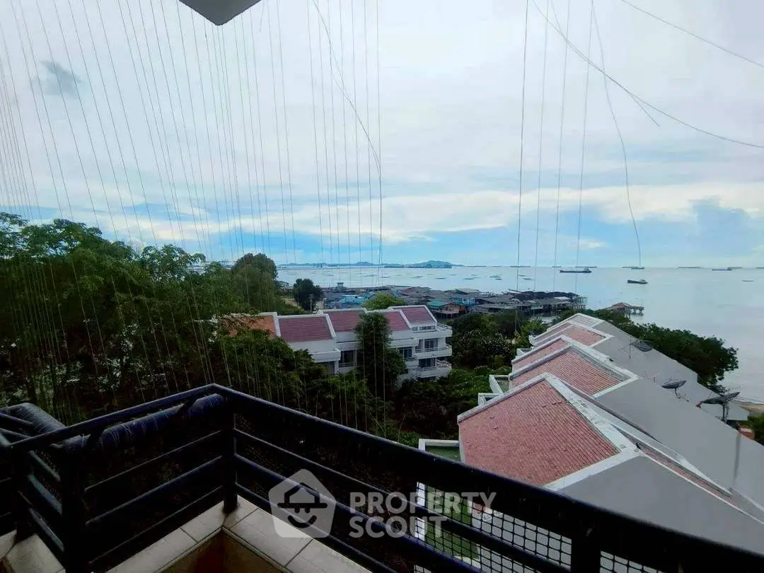 Stunning ocean view from a spacious balcony overlooking rooftops and lush greenery.