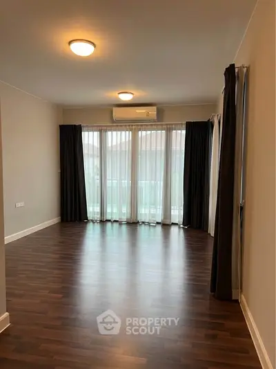 Spacious empty living room with wooden flooring and large windows