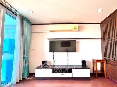 Modern living room with wall-mounted TV and air conditioning, featuring stylish furniture and natural light.