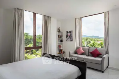 Spacious bedroom with large windows offering stunning views and cozy seating area.