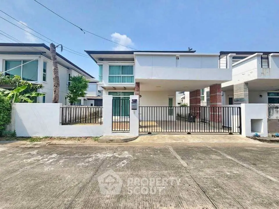 Modern two-story house with gated driveway and spacious front yard.
