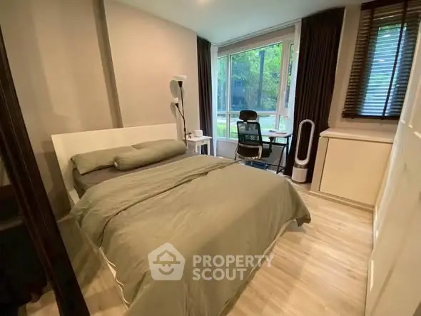 Cozy bedroom with large window and study area, featuring modern decor and natural light.