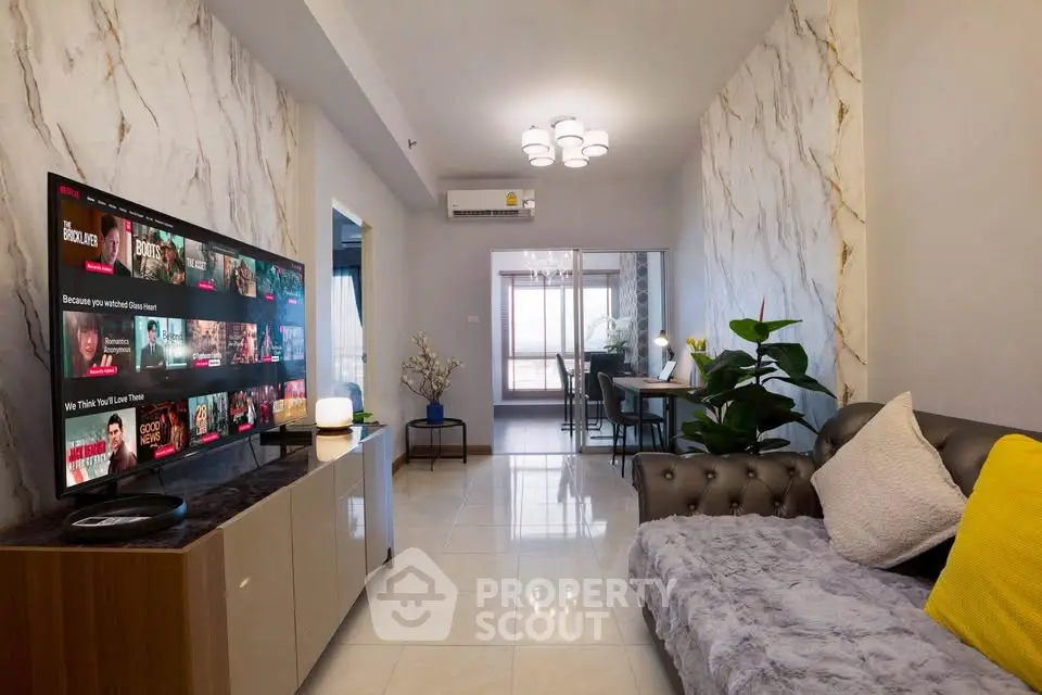 Modern living room with stylish decor and large TV, perfect for entertainment.