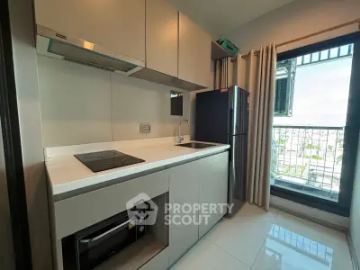 Modern kitchen with sleek cabinetry and balcony view in a stylish apartment.