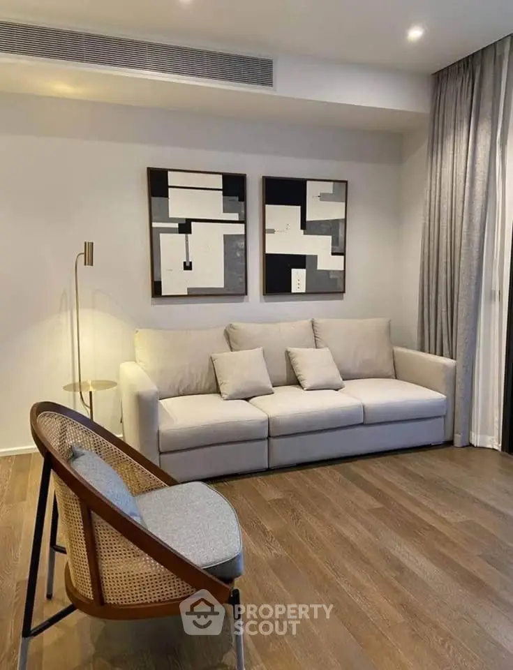 Modern living room with stylish furniture and abstract art, featuring a cozy sofa and elegant wooden flooring.