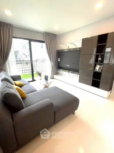 Modern living room with sleek furniture and large windows leading to a balcony.