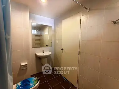 Modern bathroom with sleek fixtures and tiled walls, featuring a large mirror and shower area.