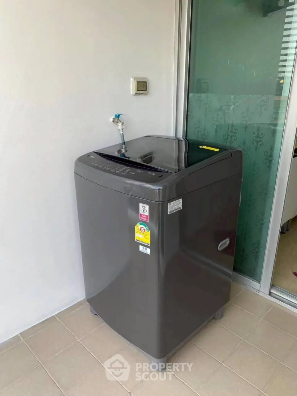 Modern washing machine on tiled balcony with sliding glass door