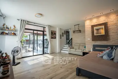 Spacious living room with modern decor and large windows opening to a patio.