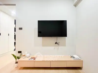 Modern minimalist living room with wall-mounted TV and sleek wooden console.