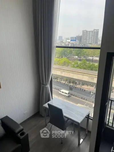 Modern apartment with large window offering city view and sleek interior design.