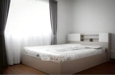 Modern minimalist bedroom with natural light and stylish curtains, featuring a sleek bed frame and wooden flooring.