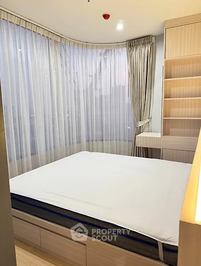 Modern bedroom with large windows and built-in storage, offering a cozy and bright atmosphere.