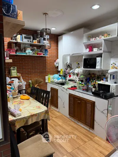 Cozy kitchen with brick accent wall and modern cabinetry, featuring a dining area and ample storage space.