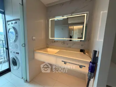 Modern bathroom with illuminated mirror and stacked washer-dryer unit