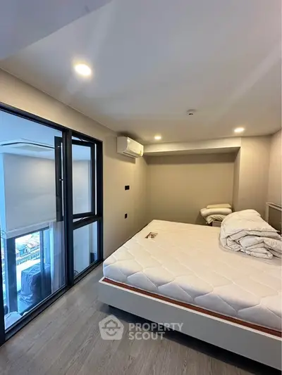 Modern bedroom with large windows and city view, featuring a comfortable bed and sleek design.