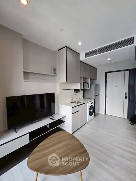 Modern apartment interior with sleek kitchen and cozy living area, featuring stylish furniture and appliances.
