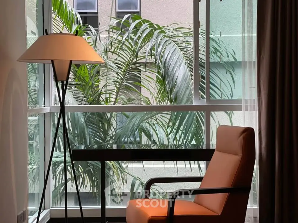 Stylish interior with modern chair and floor lamp by large window with lush greenery view.