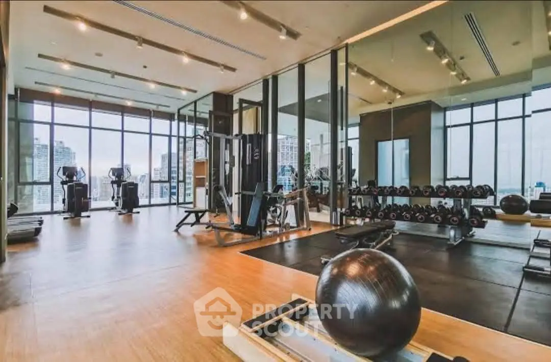 Luxurious gym with modern equipment and city view in upscale residential building.