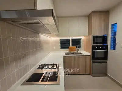 Modern kitchen with sleek appliances and gas stove in stylish open layout.