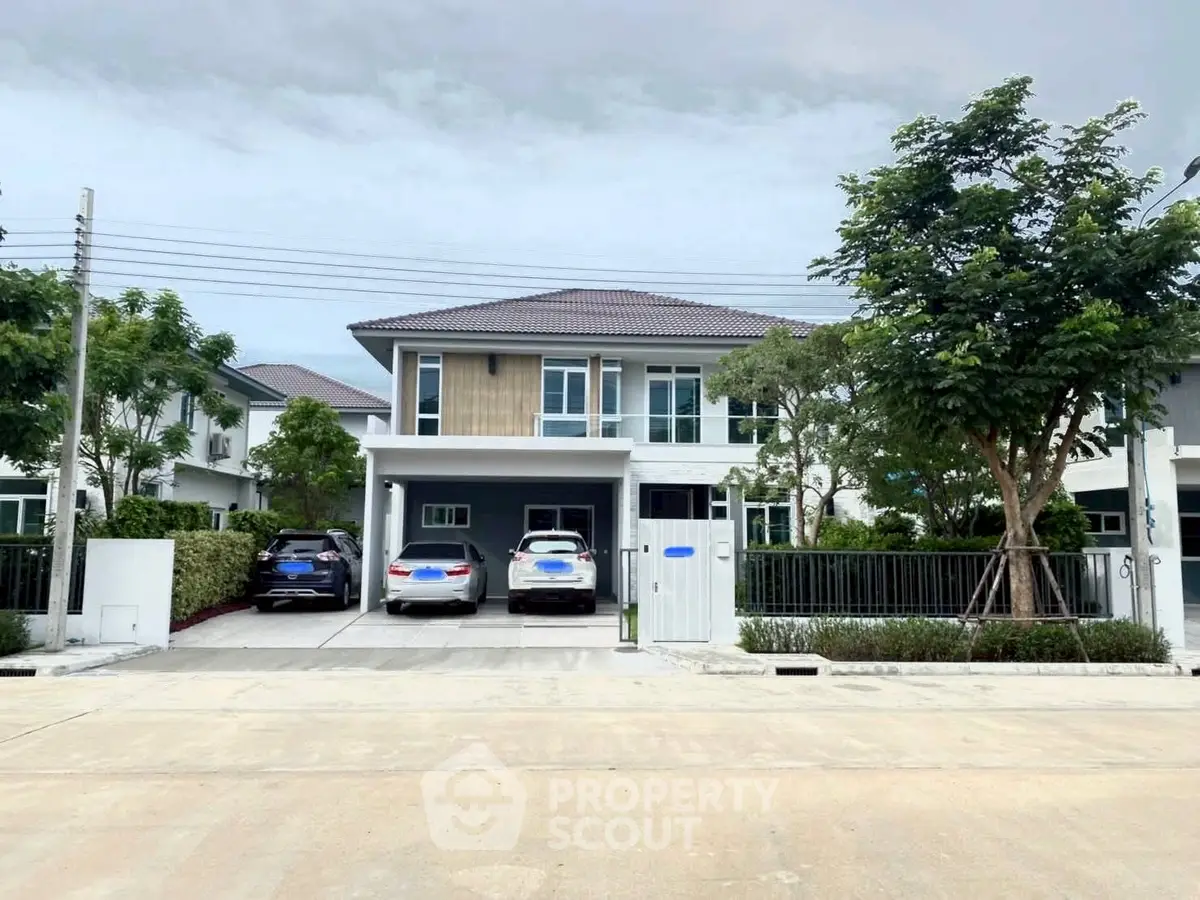 Modern two-story house with driveway and lush greenery in a suburban neighborhood.