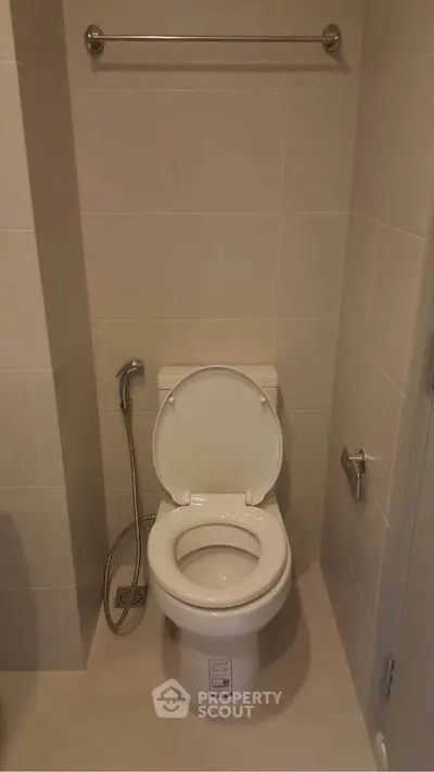 Modern bathroom with sleek toilet and bidet spray in a minimalist design.