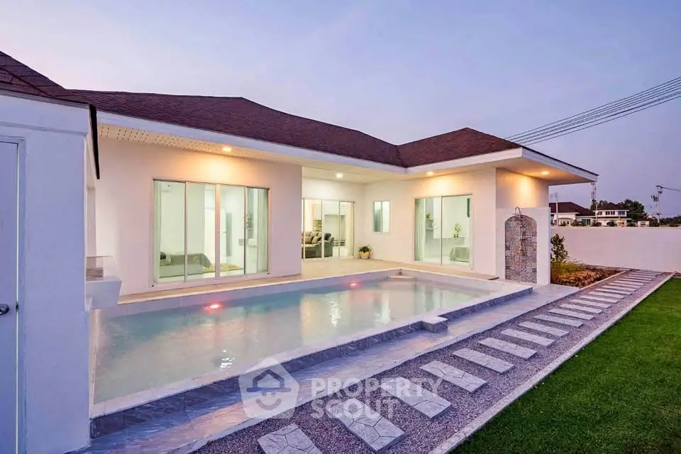 Luxurious modern home with private pool and elegant exterior lighting at dusk.