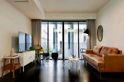 Modern living room with sleek furniture and large glass doors leading to a balcony.