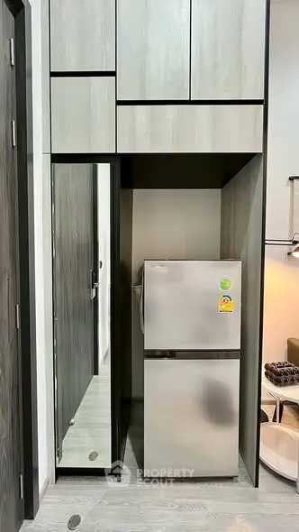 Modern kitchen with sleek cabinetry and stainless steel fridge in compact layout.
