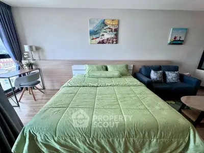 Cozy bedroom with green bedding, modern decor, and natural light in a stylish apartment.