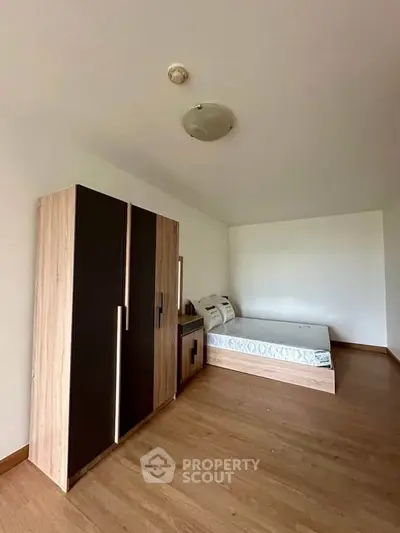 Spacious bedroom with modern wardrobe and comfortable bed, featuring wooden flooring and minimalist design.