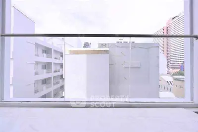 Modern urban balcony with glass railing offering cityscape views.
