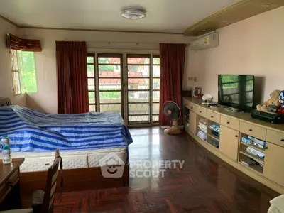 Spacious bedroom with wooden flooring, large windows, and built-in storage units.