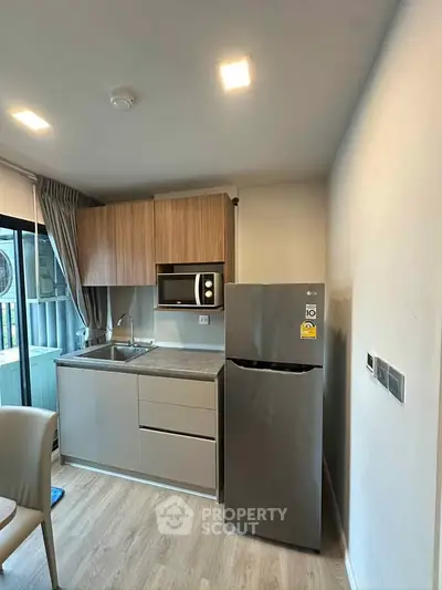 Modern compact kitchen with sleek cabinetry and stainless steel appliances in a cozy apartment setting.