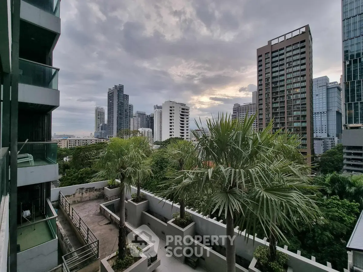 Stunning cityscape view from a modern balcony with lush greenery and towering skyscrapers.