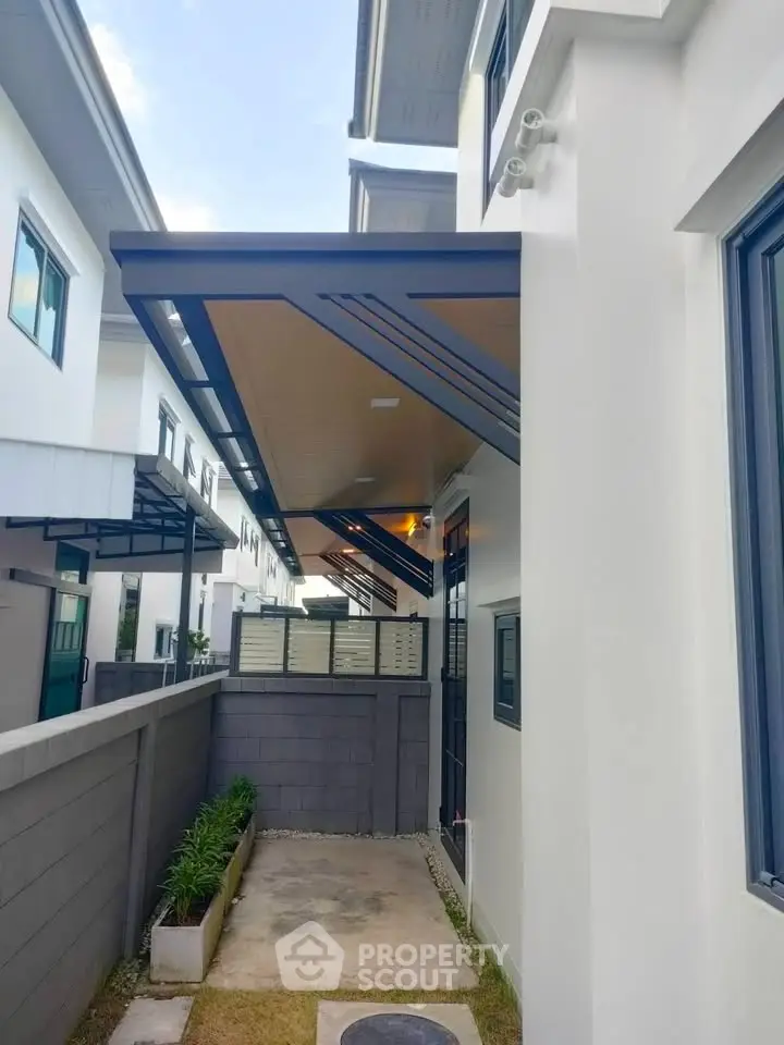 Modern townhouse exterior with sleek awnings and landscaped pathway, showcasing contemporary architectural design.