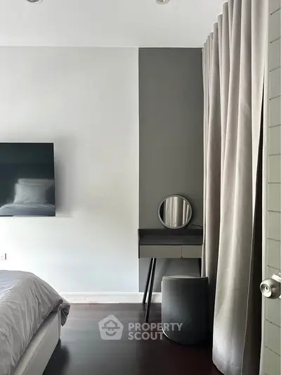 Modern bedroom with sleek design, featuring a wall-mounted TV and stylish vanity area.