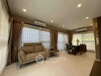 Spacious living room with elegant dining area and large windows in modern home.