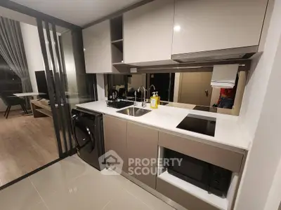 Modern kitchen with sleek cabinetry, integrated appliances, and open layout leading to living area.