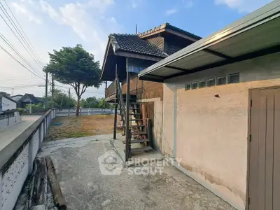 Charming rustic wooden house with outdoor staircase and spacious yard.