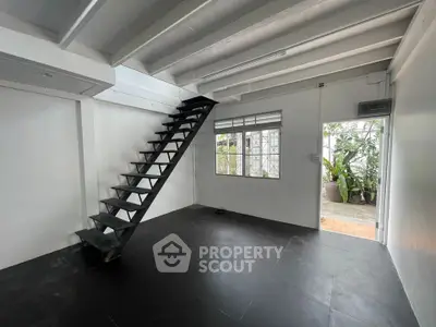 Modern minimalist interior with sleek staircase and large window overlooking greenery.